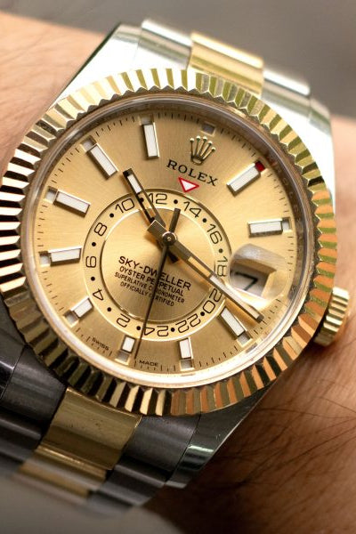Gold and silver Rolex watch on a wrist with a blurred background